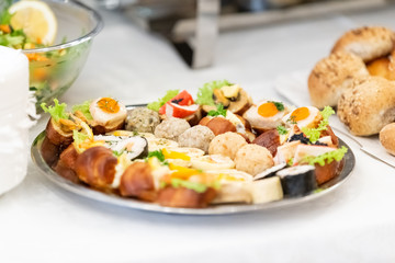 Buffet table canape plate with sandwiches and bread.