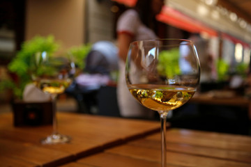 closeup of white wine glass at the table of street cafe