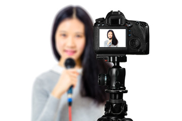 Focus on live view on camera on tripod, teenage girl   with blurred scene in background. Teenage vlogger livestreaming show concept