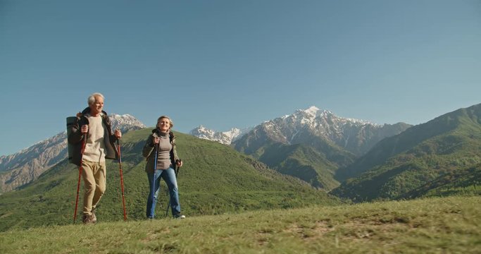 Mature caucasian couple on vacation, having a hike in spring mountains, spending time together after retirement together travelling - tourism, pension concept 4k