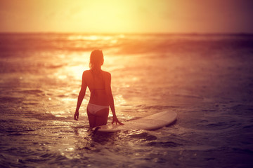 Fototapeta premium Attractive woman standing in ocean with surfboard