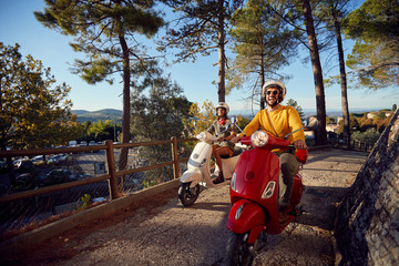 Happy couple riding on a scooter in old European town on vacation.