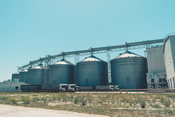Obraz premium Svetlovodsk, Ukraine – 27 May, 2018: Modern Agricultural Silos against blue sky. Storage and drying of grains, wheat, corn, soy, sunflower. Agricultural silo at feed mill factory