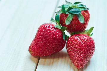 Red juicy strawberries on a light wooden table. with copy space. close-up view.