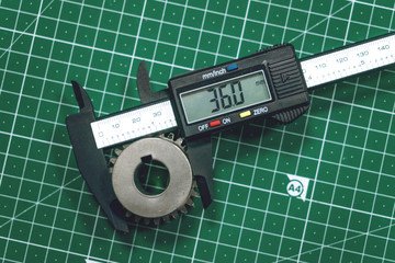 Metal gear measurement process. Measuring steel detail, gear with digital Vernier Caliper at...