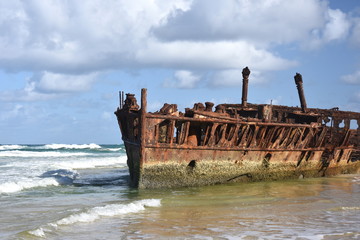 The rusty wreck of the vessel Maheno on the shores of Fraser Island (Queensland, Australia). The antique rusty and damaged boat and corrosion in the ocean sea.