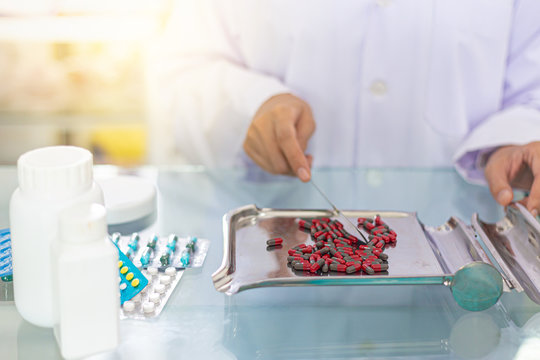 Pharmacist is counting medical pills on stainless steel tray at drugstore. Health care and medical concept. 