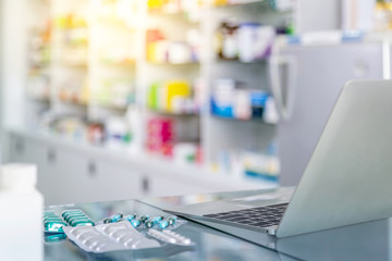 Medicine and computer on payment counter with blurred medicines shelves background. Healthcare,...