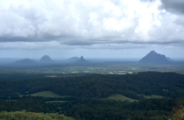 Obraz premium Panoramic view of Glass House Mountains National Park on Sunshine Coast (Queensland, Australia). The Glasshouse Mountains are silhouetted in the afternoon sunlight.