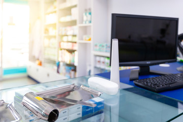 omputer and pill counting tray on payment counter with blurred medicines shelves background.