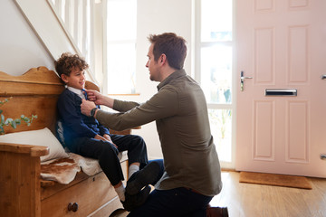 Single Father At Home Getting Son Wearing Uniform Ready For First Day Of School