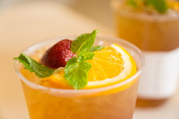 Beverage mocktail orange flavor, mixed with lime and strawberry with ice decorated with mint leaves in a plastic glass.