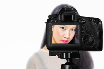 Focus on live view on camera on tripod, teenage girl   with blurred scene in background. Teenage vlogger livestreaming show concept
