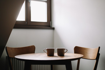 Two cups on wooden table. Dining room with table and two chairs. Modern minimal Scandinavian nordic interior. Morning coffee