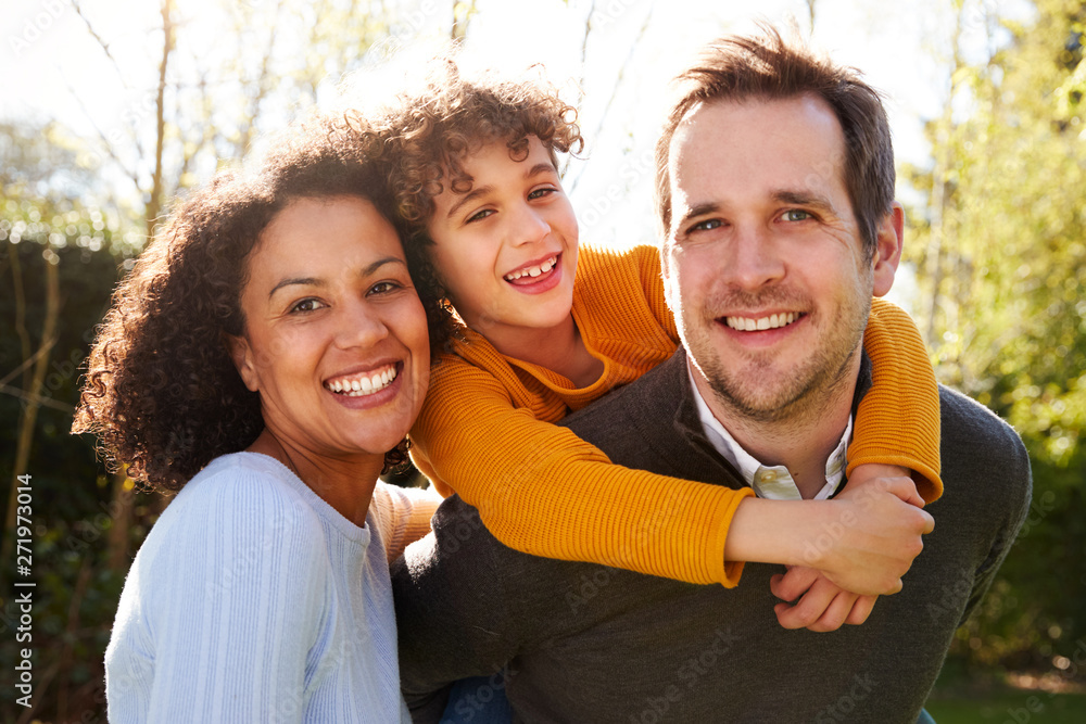 Wall mural Outdoor Portrait Of Smiling Family In Garden At Home Against Flaring Sun