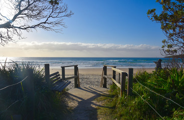 Old wooden walkway path entrance to the beach. Sandy ocean beach entrance. Sea beach wooden walkway path entrance. Sandy ocean beach entrance.