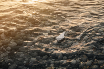 Naklejka premium Alone paper boat floats in waves on the water.