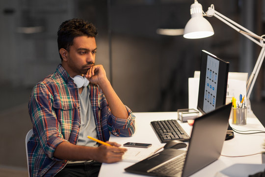 deadline, technology and people concept - creative man with laptop computer working at night office