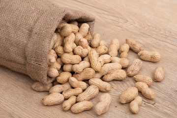 Overturned scattered peanuts, close up photo of poured roasted peanuts on wooden table