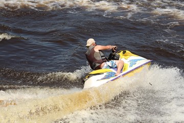 Active Senior Man riding a Personal Watercraft wearing a life jacket
