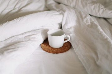 Breakfast in bed. Coffee cup in the morning on the bed background. Bedding sheets with copy space. Flat lay, top view. 
