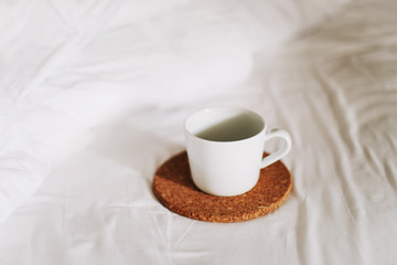 Breakfast in bed. Coffee cup in the morning on the bed background. Bedding sheets with copy space. Flat lay, top view. 