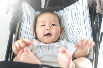 little happy asian baby smiling in sitting stroller