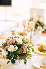 Gorgeous luxury wedding table arrangement, floral centerpiece close up. The table is served with cutlery, crockery and covered with a tablecloth. Wedding party decoration with pink and white flowers.