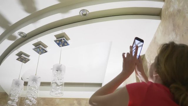 Water damage. concept of flooding the apartment and property insurance. a woman takes a photo on the phone as water drips from the ceiling of her apartment
