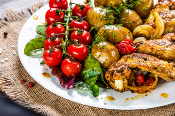 Roast chicken wings, baked potatoes and vegetables