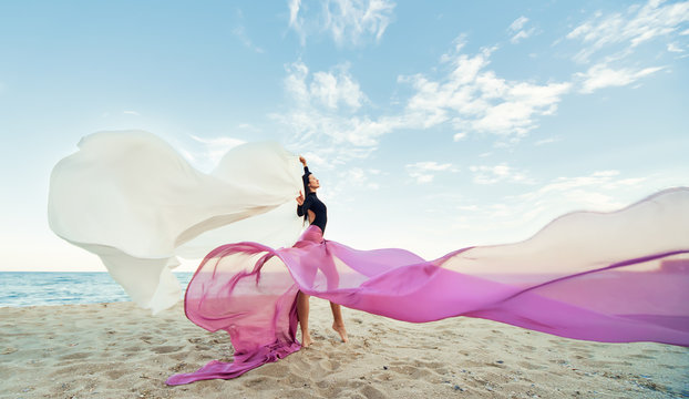 Slim Woman at the beach with long pink fabric. Sky background at the summer. Classic dancer on the nature