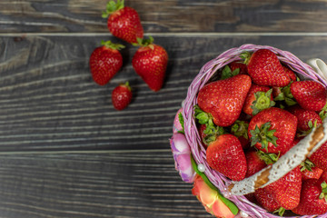 Strawberries in a small basket on the wooden table. Place for your logo or text