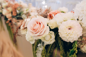 Gorgeous luxury wedding table arrangement, floral centerpiece close up. The table is served with cutlery, crockery and covered with a tablecloth. Wedding party decoration with pink and white flowers.