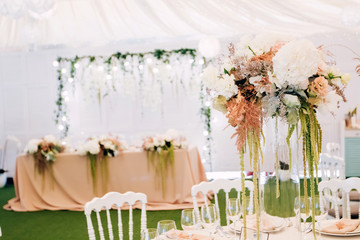 Gorgeous luxury wedding table arrangement, floral centerpiece close up. The table is served with cutlery, crockery and covered with a tablecloth. Wedding party decoration with pink and white flowers.