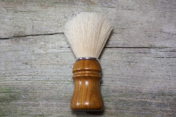 Close-up of fancy boar shaving brush with intricate wooden handle, laying in rustic wooden surface.