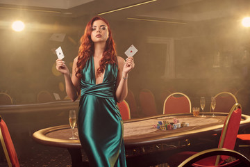 Fototapeta na wymiar Young beautiful woman is posing against a poker table in luxury casino.