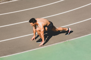 overhead view of mixed race sportsman preparing to run at stadium