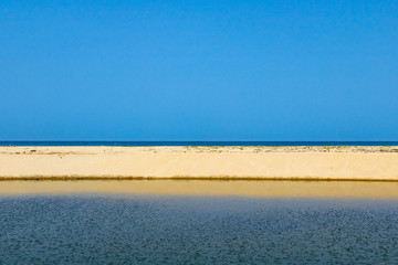 straight shore line at the sea with blue sky