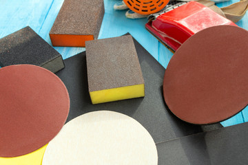 Abrasives, sanding paper sponges and sanding wheel respirator composition on the blue wooden background close up