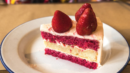Cake with cream and fresh strawberries on the plate close-up