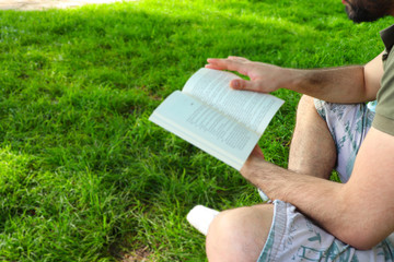 The young man reads book on the grass field