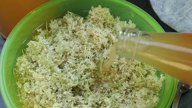 Prepare elder berry flower heads to making jam of it. Mixing apple juice into bowl.