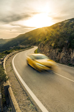 yellow car blur speeding in mountain road