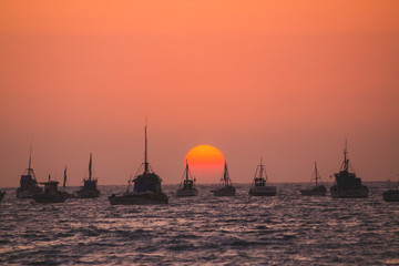 sunset over mancora beach with fisher boats, peru