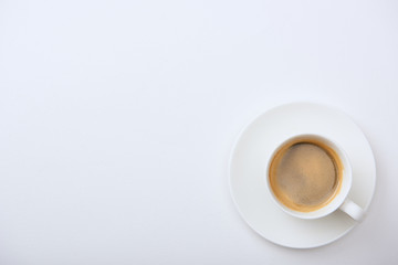 top view of delicious coffee with foam in cup on saucer on white background with copy space