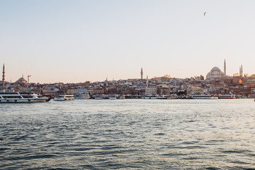Fototapeta na wymiar Scenic view of Istanbul and the Galata Tower from the Bosphorus Bay, shot on a sunny day. Vintage fishing boats on the coast in Istanbul. Passenger ferry through the Bosphorus