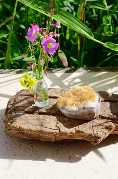 Flowers and crystals! Healing citrine crystal cluster, mini glass vase of fresh cut flowers. Nature and healing crystals shot at wood table outside. Cute witchy bohemian outdoorsy whimsical display