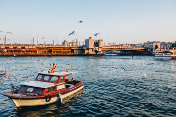 Scenic view of Istanbul and the Galata Tower from the Bosphorus Bay, shot on a sunny day. Vintage fishing boats on the coast in Istanbul. Passenger ferry through the Bosphorus