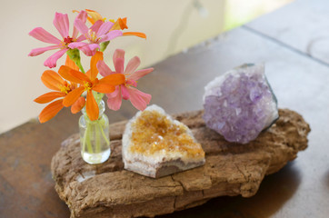 Amethyst and Citrine clusters on a wooden table, small vase of fresh flowers. Shot on macro lens in natural lighting. Bright colors, healing crystal clusters. Hippie natural healing and fresh herbs. 