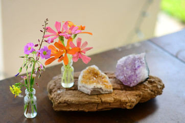 Amethyst and Citrine clusters on a wooden table, small vase of fresh flowers. Shot on macro lens in natural lighting. Bright colors, healing crystal clusters. Hippie natural healing and fresh herbs. 